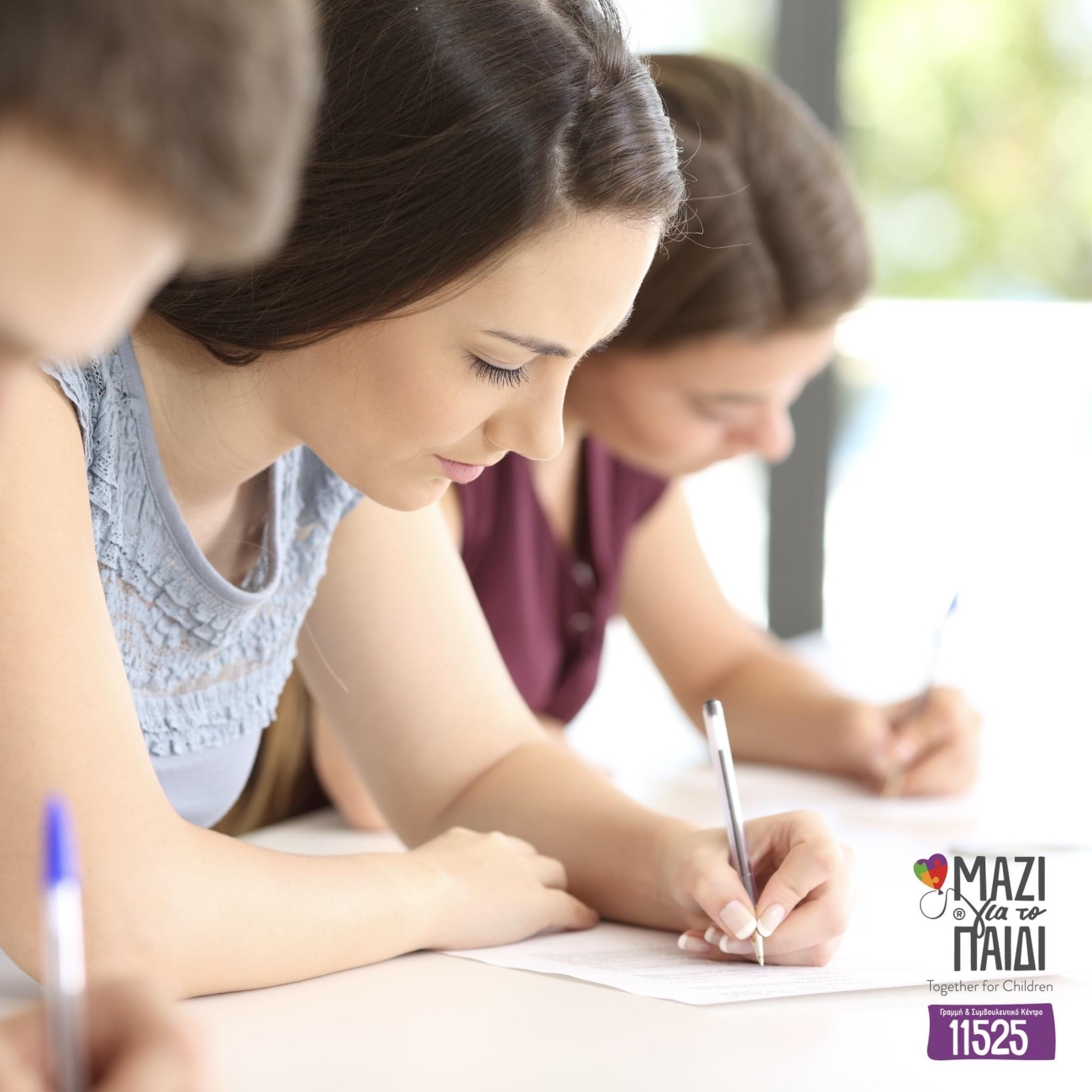 Εικόνα που παρουσιάζει νεαρούς μαθητές να δίνουν εξετάσεις γραπτώς